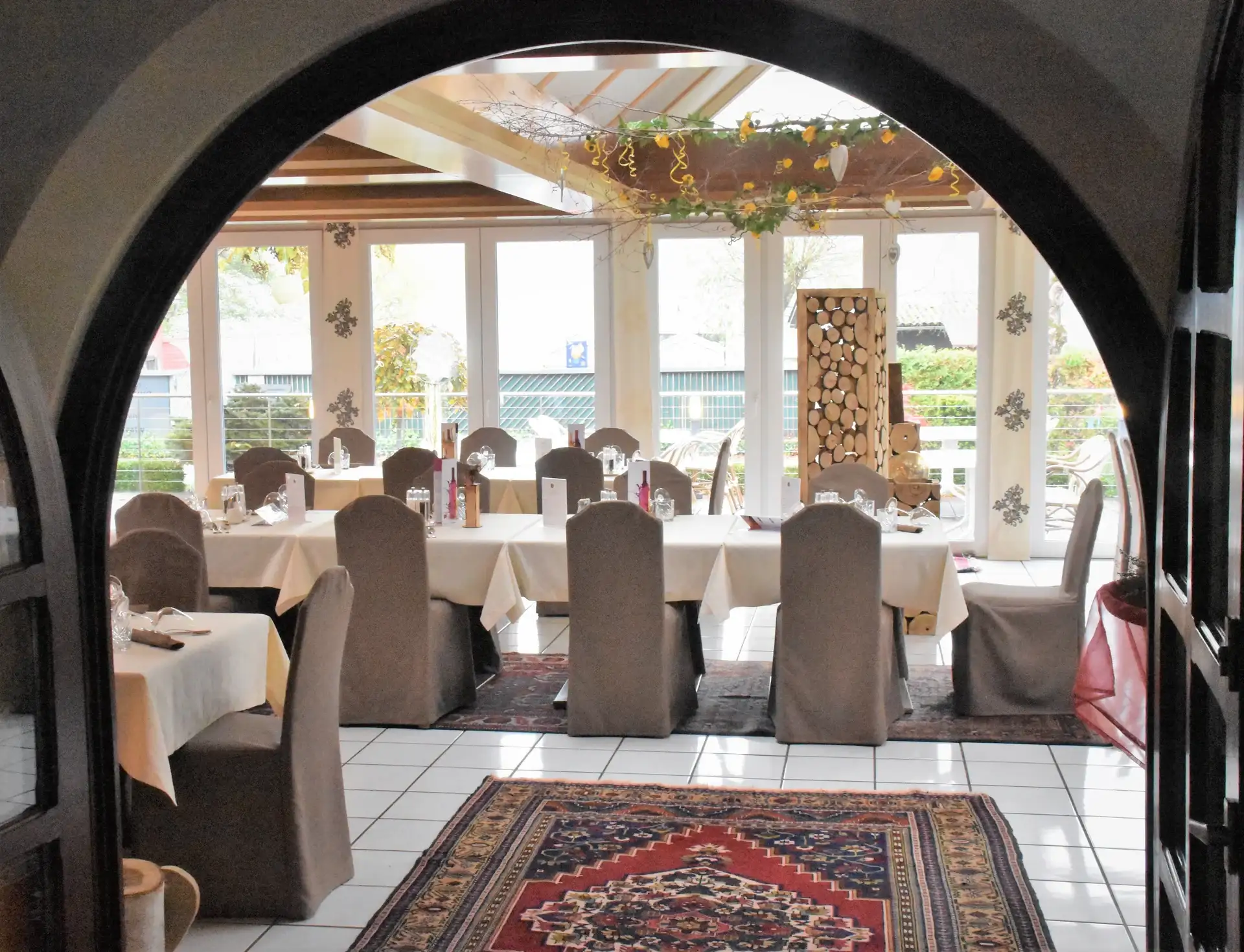 Blick durch einen Rundbogen in den festlich gedeckten Innenraum des Restaurants Kastale