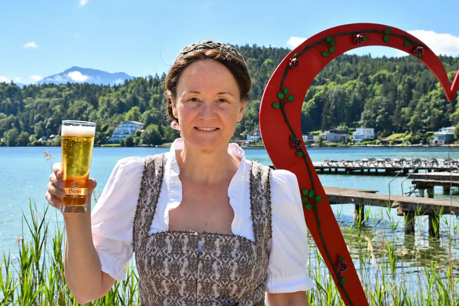 Silvia in dirndl con un bicchiere di birra in riva al lago Klopeiner See
