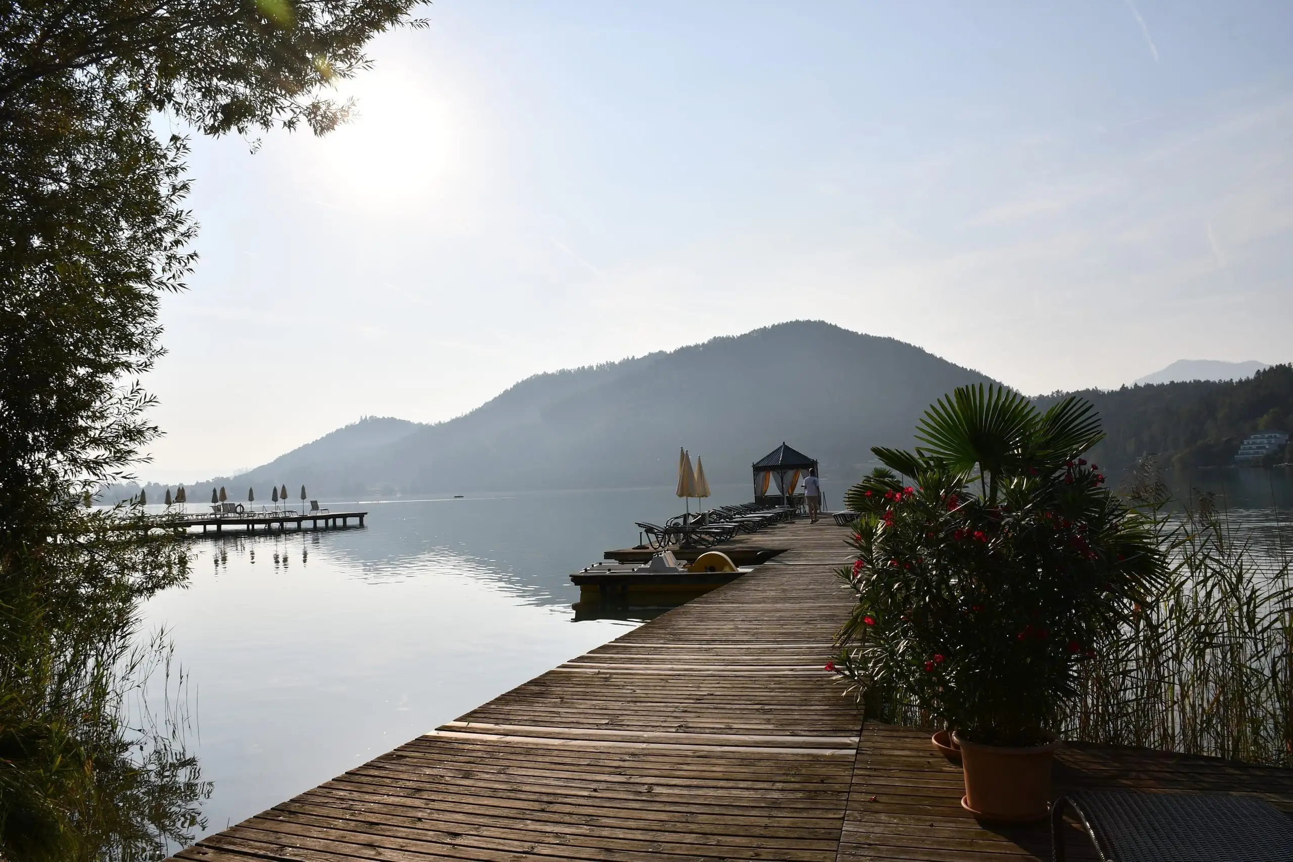 Sonnenliegen und Holzsteg am Klopeinersee im Morgenlicht